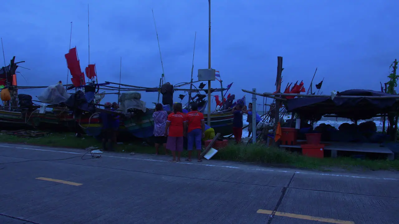 People protecting colorful wooden boat in strong winds in Songkhla Thailand evening blue light