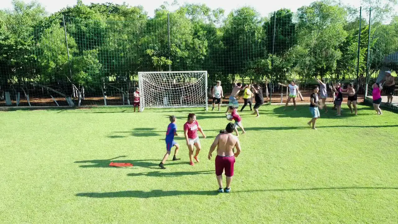 Hispanic family playing soccer on the footballfield while one of the females kicks the ball