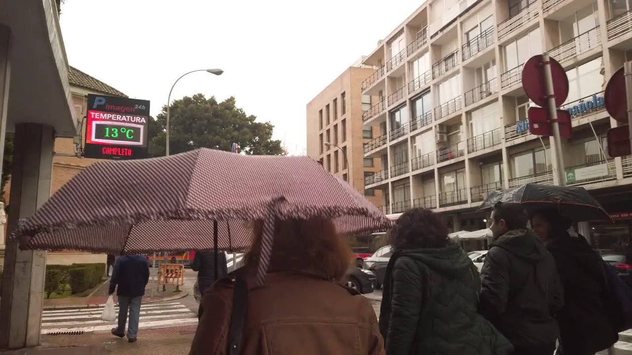 Walking behind people with umbrellas on rainy day in Seville Spain SLOWMO