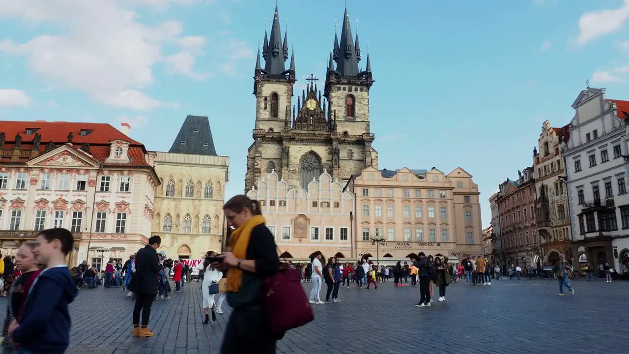 Tourists and locals walking over old town square on a sunny day in front of the church