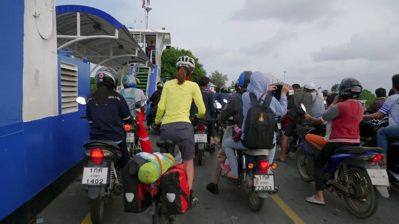 Asian people on motorcycles and bicycles exiting the ferry boat Songkhla ferry Thailand