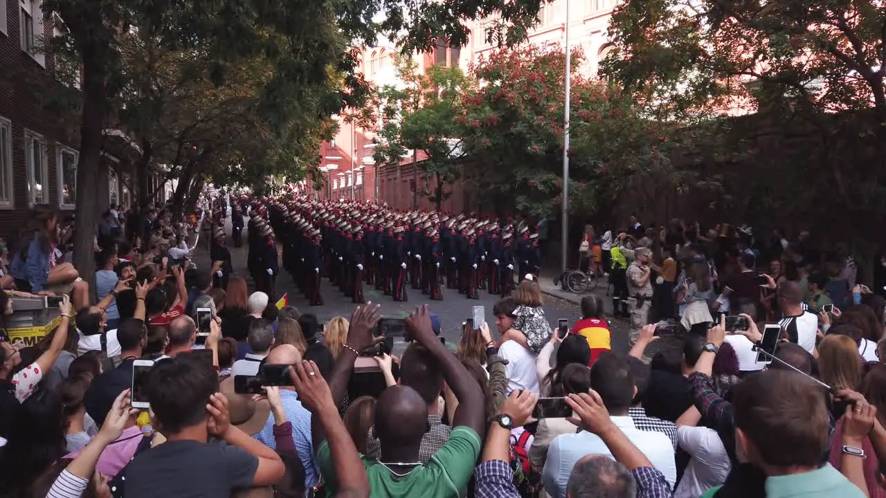 A shot of many people recording with their smartphones a group of soldiers in a parade