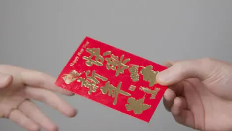 Close Up Shot of One Hand Taking a Red Packet from Another On Chinese New Year