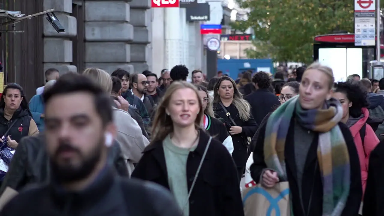 In slow motion people walk along a busy on Oxford Street during the day