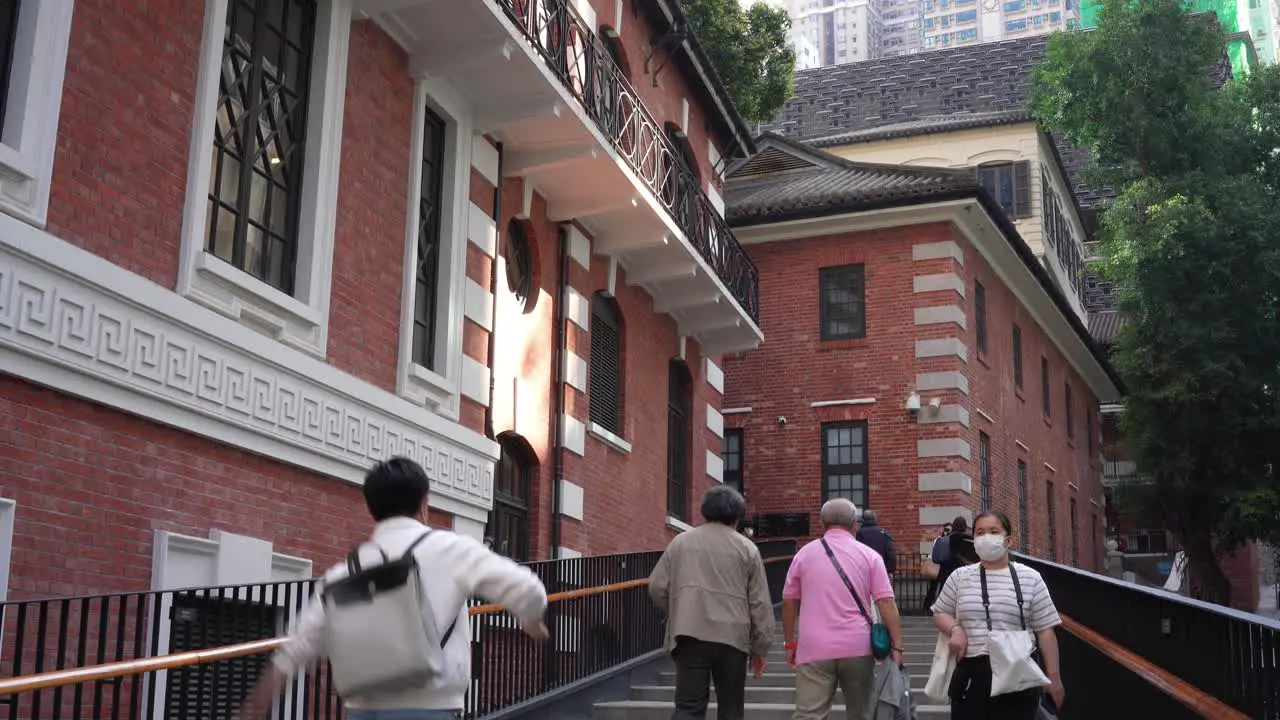 People in Asia with face masks walking up the stairs towards Tai Kwun entrance in Hong Kong