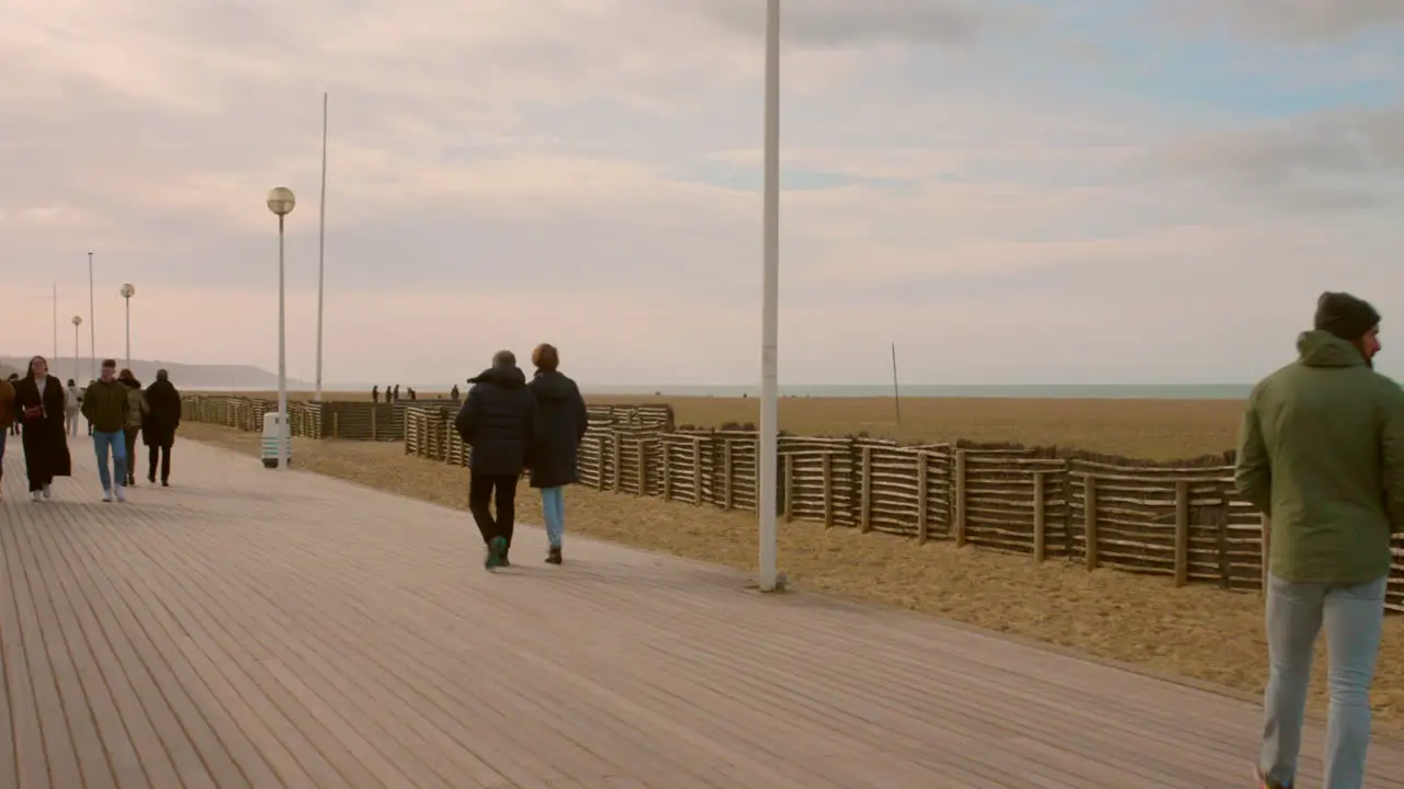 Shot of people passing by along the seaside in Promenade des Anglais Deauville France on a cold winter evening