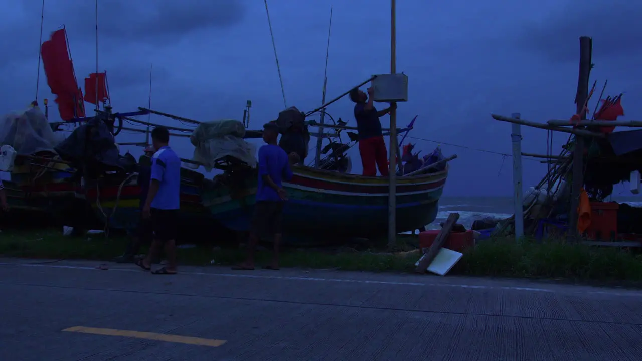 People caring for traditional wooden boats in dangerous windy weather at night Songkhla in Thailand