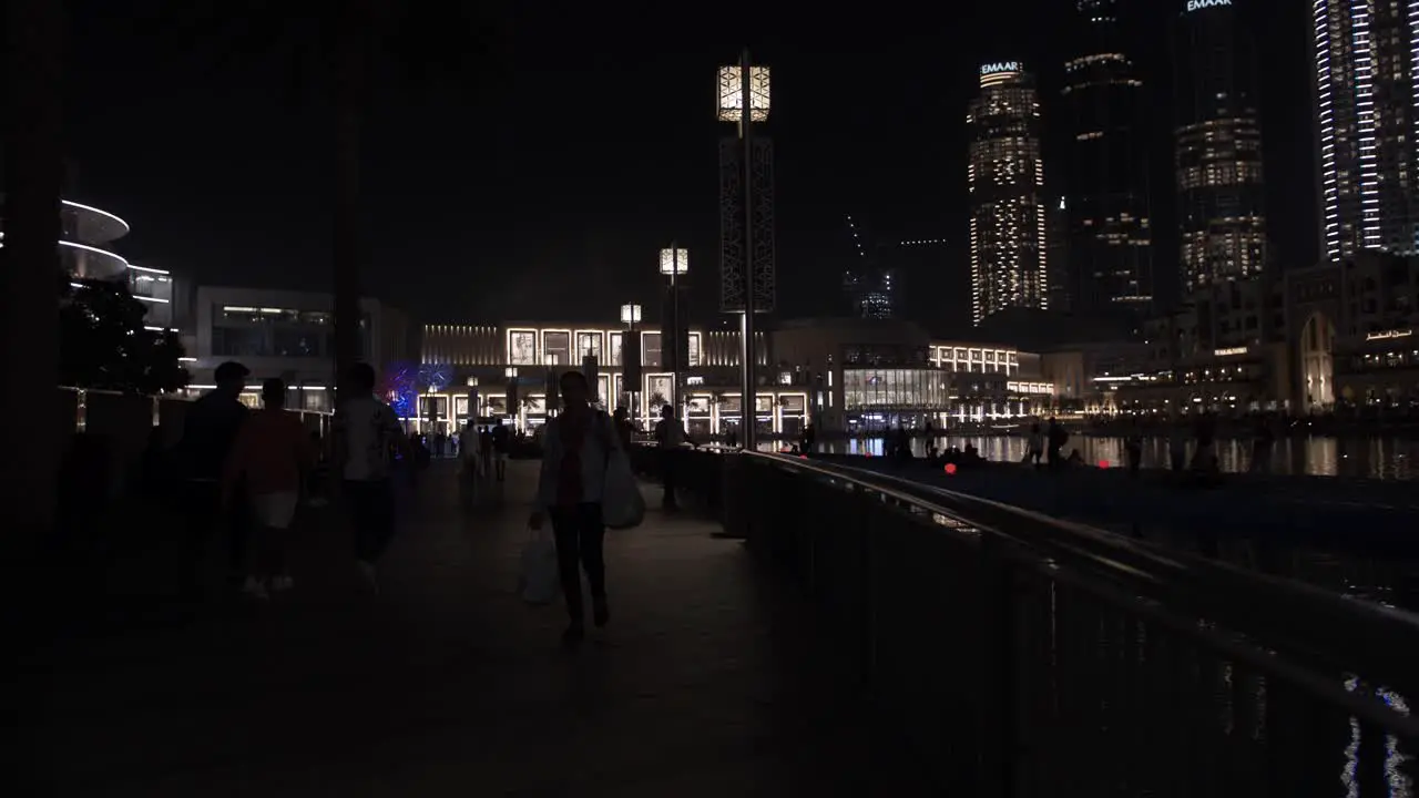 Crowds of people families walking shopping at the Dubai mall in Downtown Dubai UAE with skyscrapers and buildings lit up at night