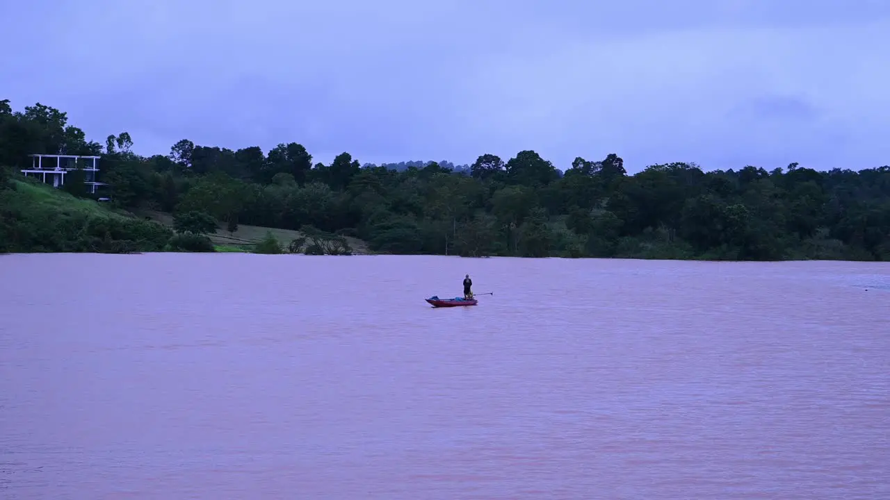 Fisherman trying to fish on a flooded lake with his motorized longboat in Wangnamkaew Nakhon Ratchasima Thailand