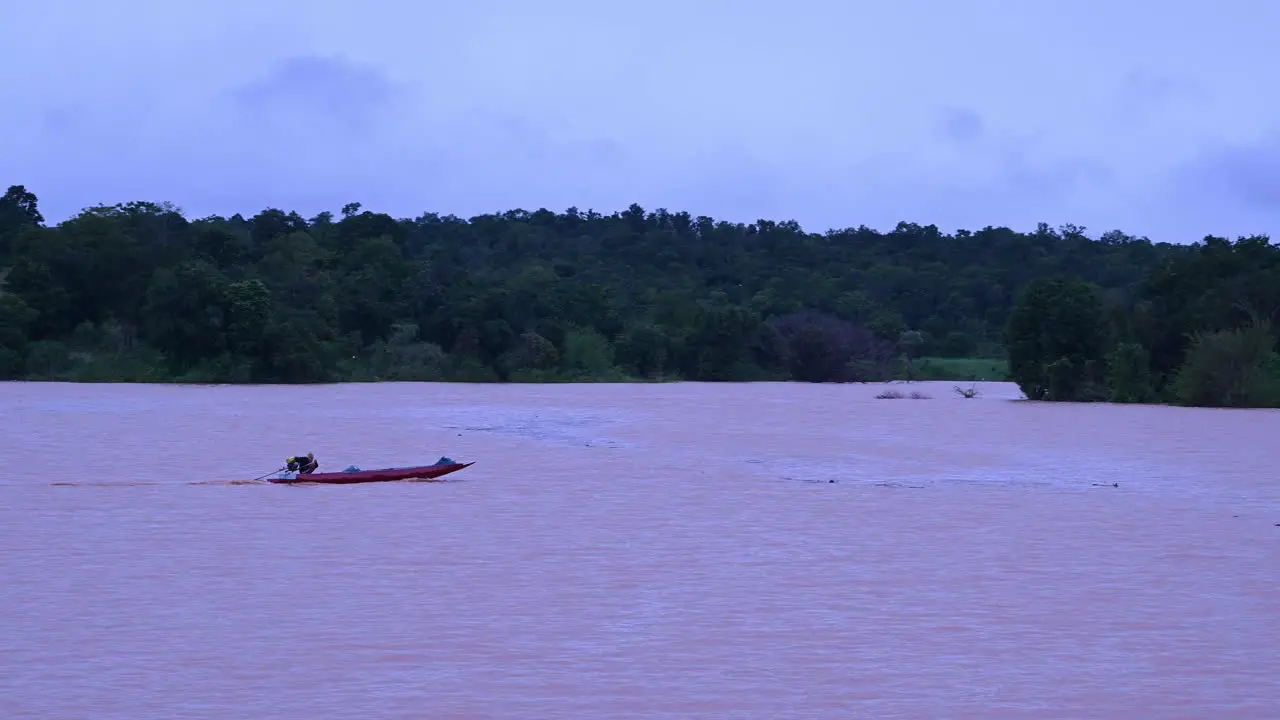 Fisherman navigating a flooded lake speeding towards the right side of the frame and then turns to the left as captured in Wangnamkeaw Nakhon Ratchasima Thailand