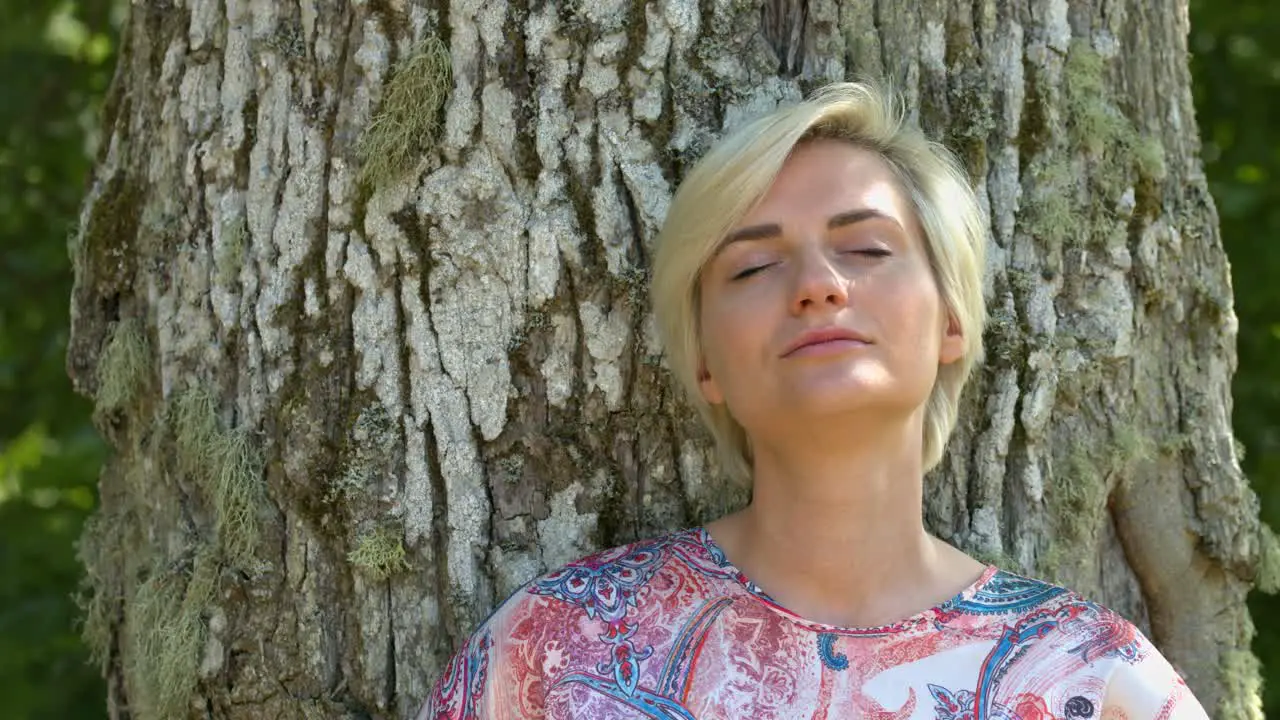 A woman standing alone in the nature calming her mind to make it at peace by closing her eyes in a meditation moment