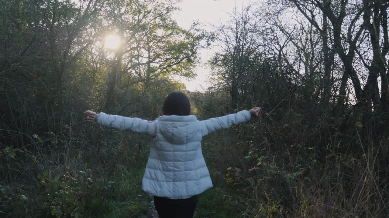 Rear View of An Asian Woman Stretching and Walking Down a Country Path