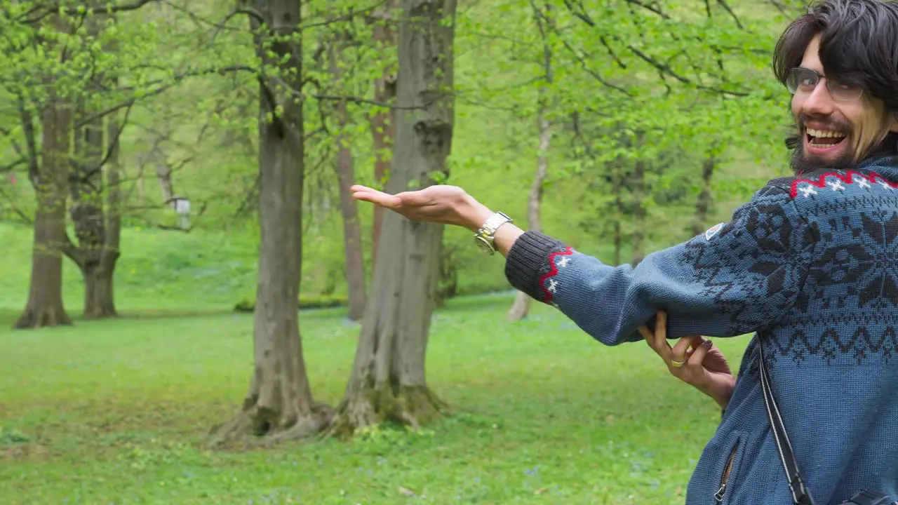 Enthusiastic young man feeds Eurasian blue tit passerine bird from hand at park