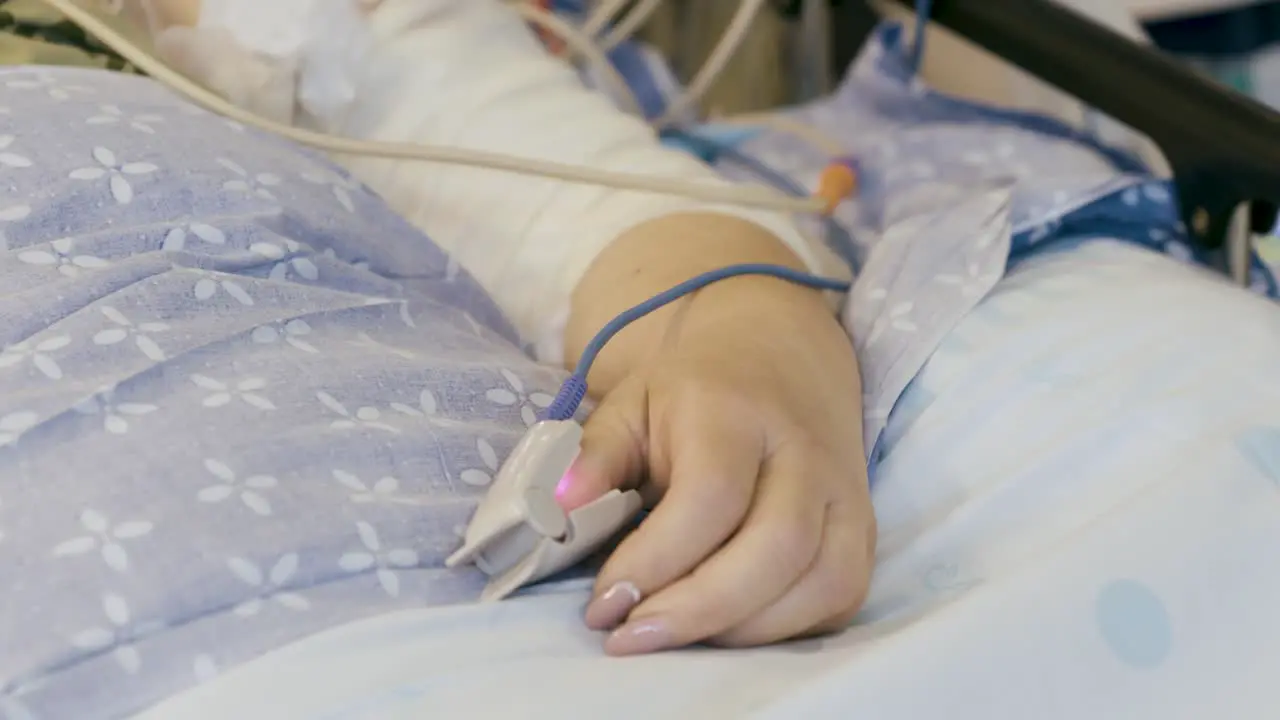 Pulse Oximeter Clipped On The Thumb Of A Covid Patient Lying On The Hospital Bed close up