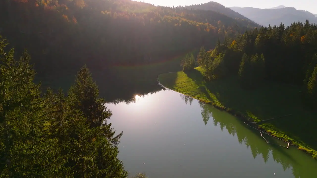 Autumnal woodland alpine trees aerial view over Sylvenstein lake reflecting mountain peaks at sunrise