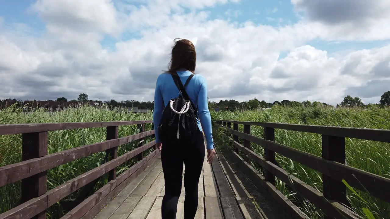 Cinematic shot of a woman walking on a lagoon dock the wind moves her hair and the environment