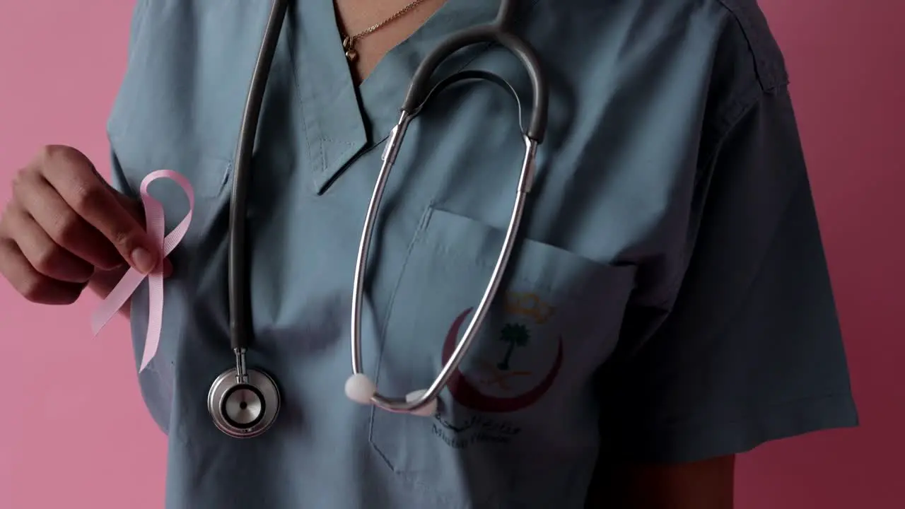 Nurse with pink ribbon during as international symbol of breast cancer awareness moral support concept