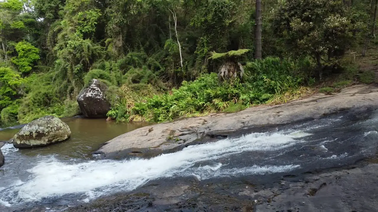 Beautiful sequence shot of drone descending a waterfall very close to the water with trees and nature around