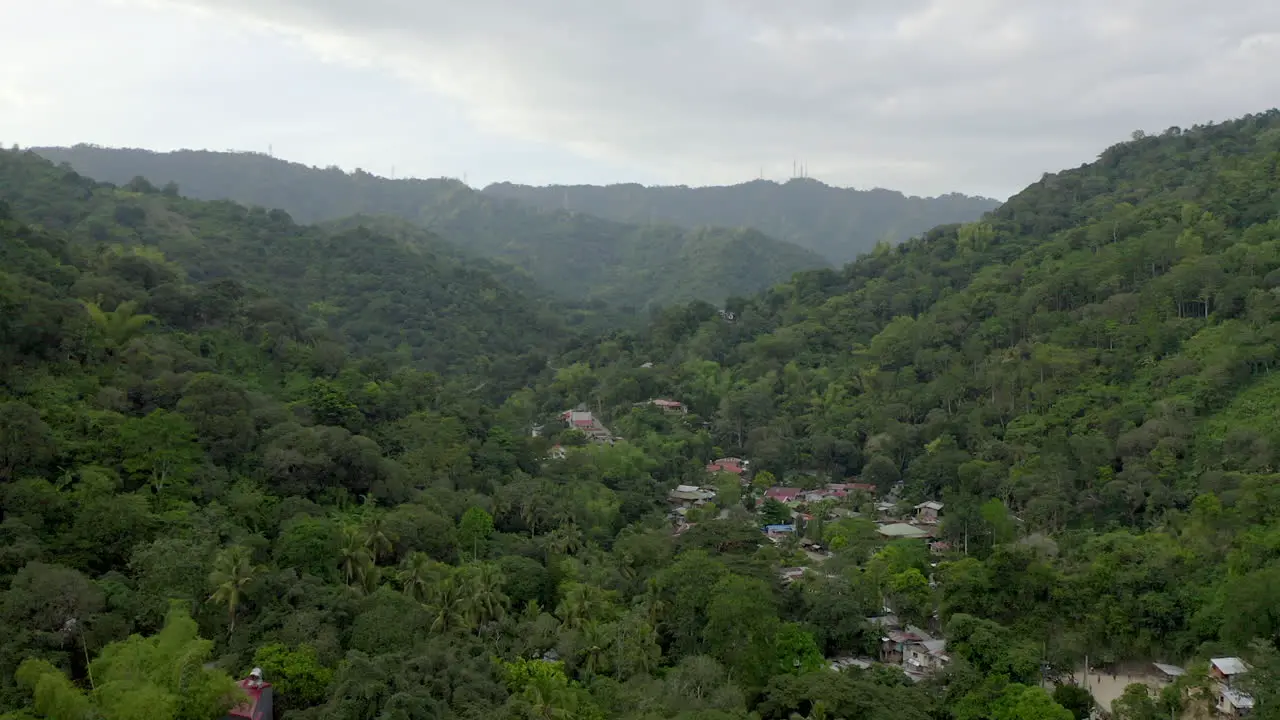 Drone video from above with houses built in green jungle in a tropical climate