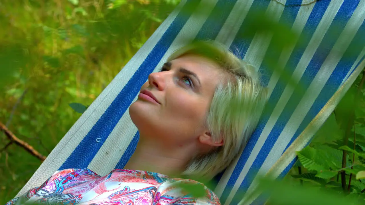 A woman relaxing in the sunshine on a sleep swing tree bed in nature with a positive attitude