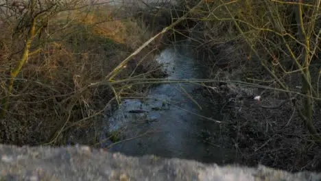 Pedestal Shot Rising Up Over Low Wall Revealing Flowing Stream