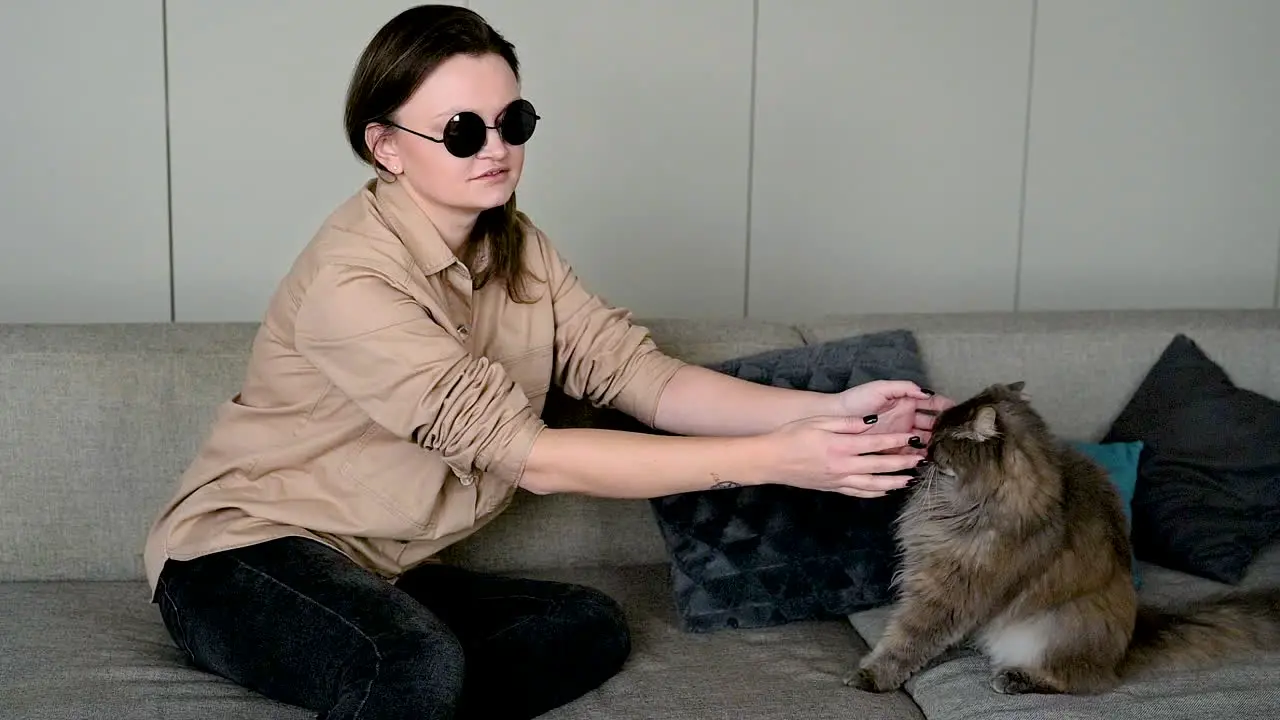 Blind Woman In Sunglasses Sitting On Sofa At Home And Petting Her Cat 1