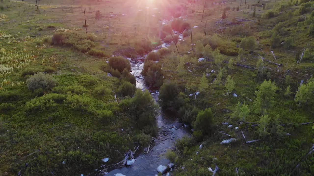 Aerial low shot over the course of a river in the Grand Teton Park with sun beams in the top of the shot