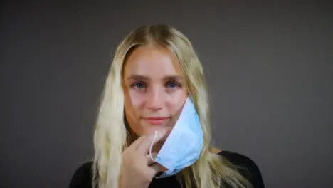 Young Blonde Woman Removes Face Mask Smiles