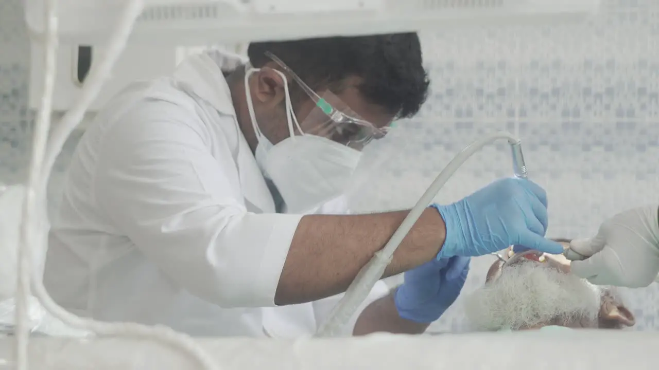 Dental surgeon doing dental treatment on a old man