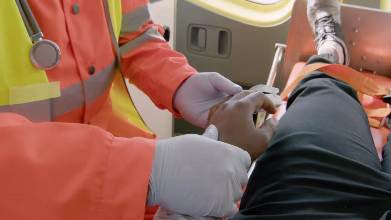 Paramedic Wearing Facial Mask Touching The Hand Of A Patient Lying On The Stretcher Inside An Ambulance 1