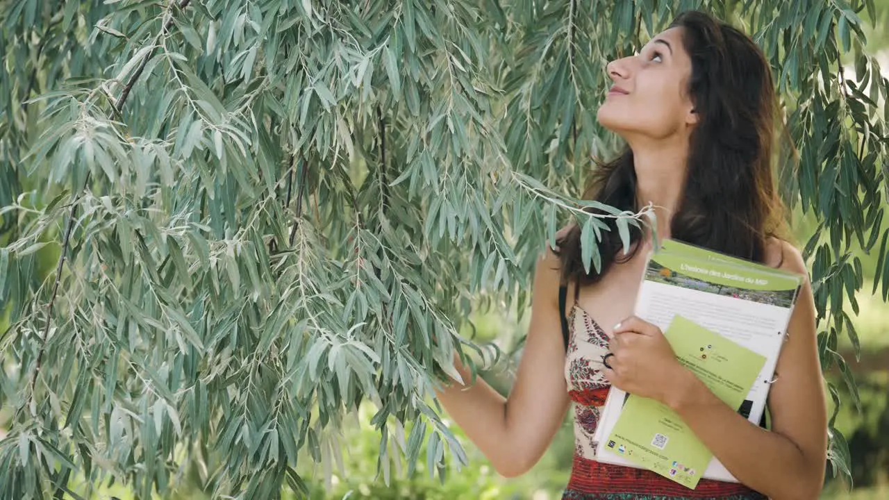 Happy visitor woman walking under a tree in botanical gardens of the perfumery museum