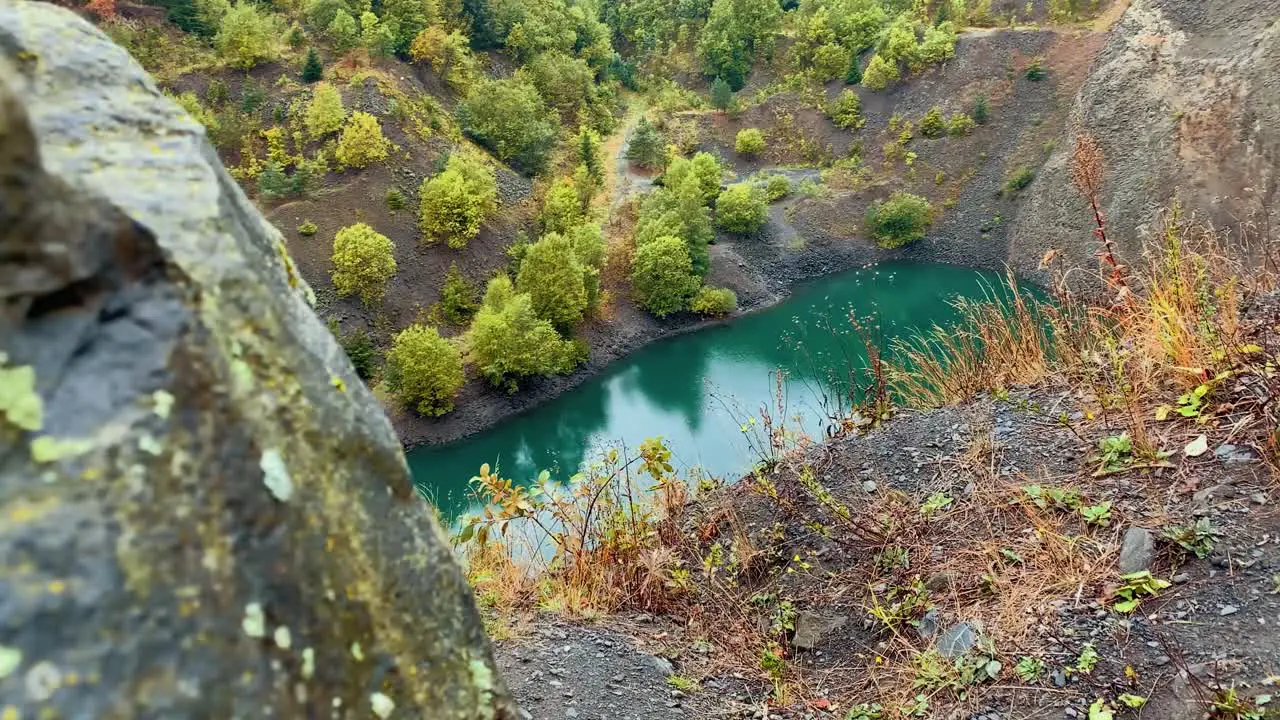 a small beautiful lake in a mountain surrounded by rocks and greenery colorful