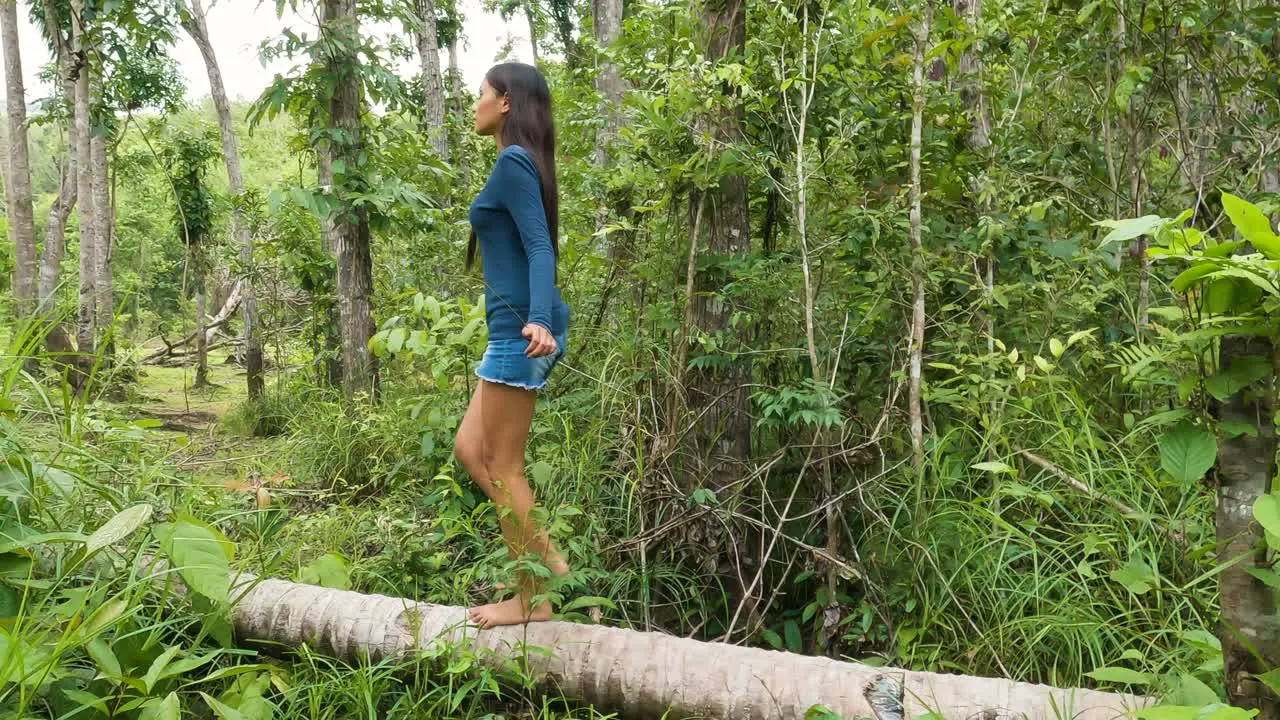 Asian Young Girl Walking Into Fallen Coconut Tree Trunk In Wilderness