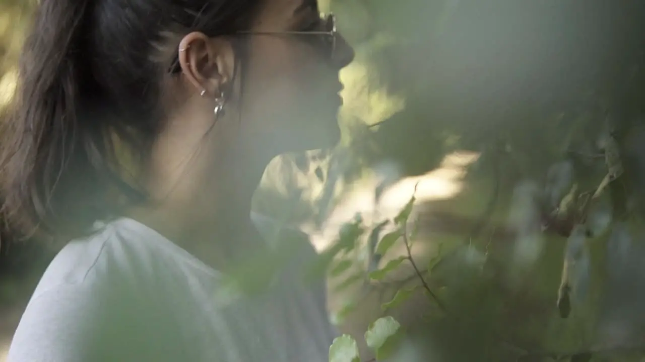 Slowmotion shot of a beautiful female looking at the colourful leaves on the branches