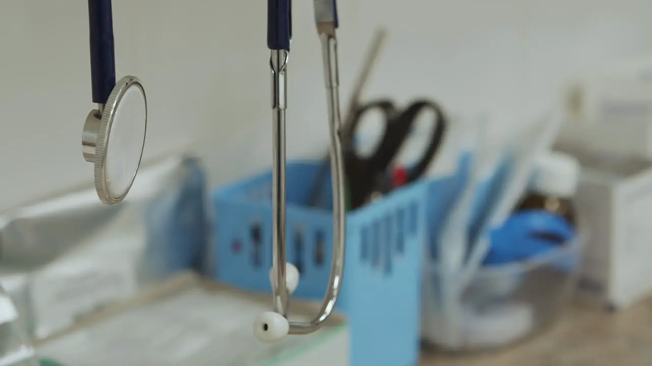 Doctor stethoscope hangs in foreground over sterile medical workspace close-up