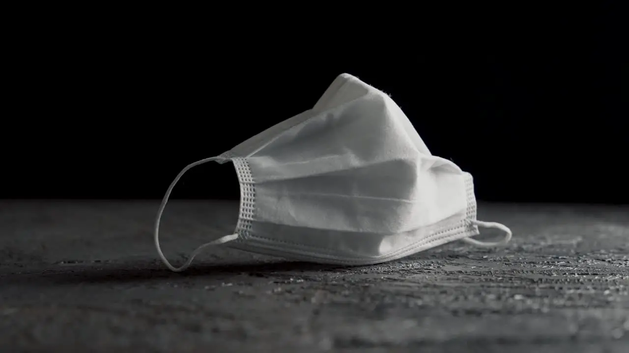 Face mask in white on a table with black background filmed on a slider