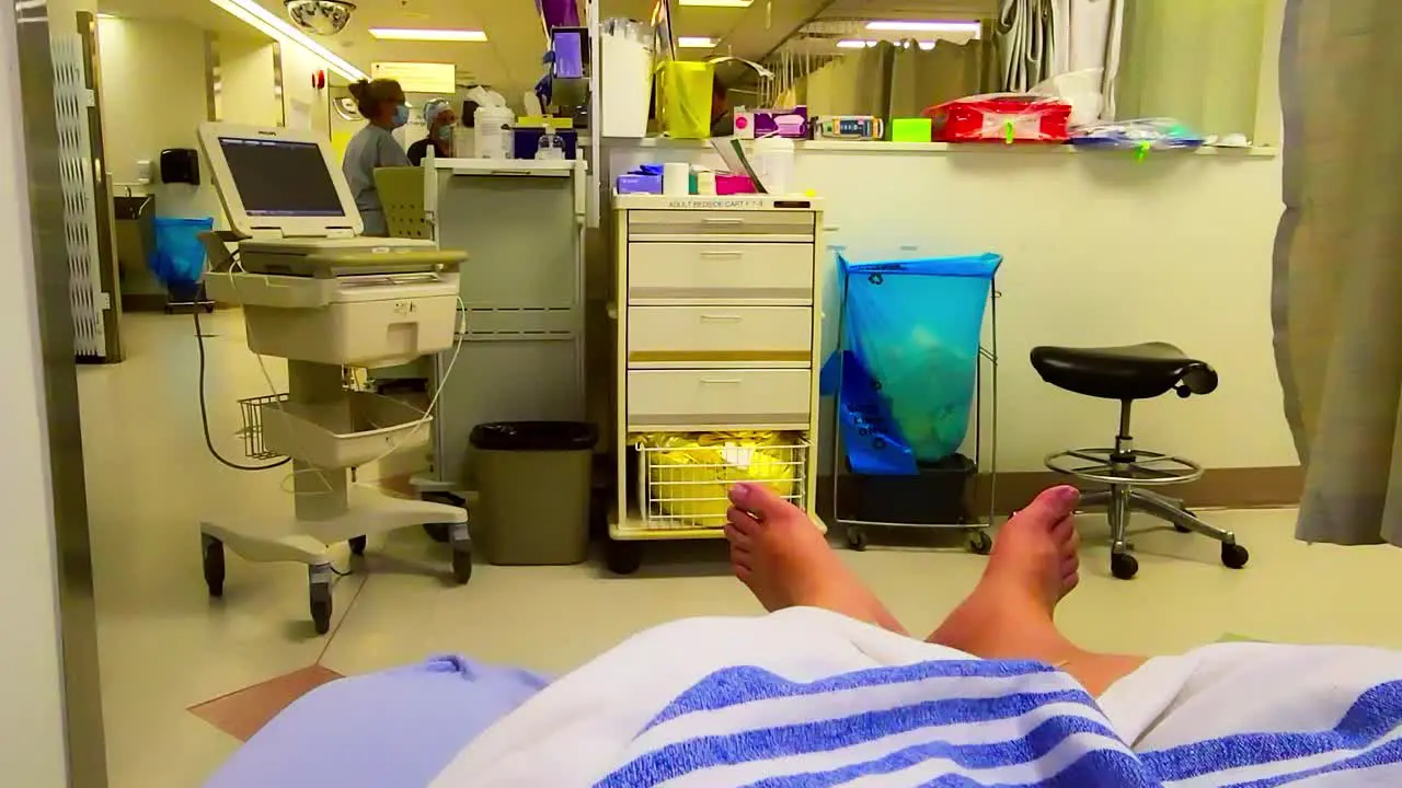 olive skinned man feet stick out of hospital bed in the emergency ward as he awaits Covid-19 results while entire body attached to electronic cables for special readings at the University of Alberta