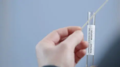 Over the Shoulder Shot of Person Placing Used Swab In Test Tube During Home COVID Self Test