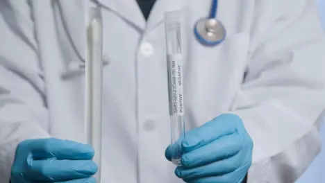 Close Up Shot of Medical Professionals Hands Holding COVID Test Tube and Swab 