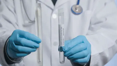 Close Up Shot of Doctor Walking Towards Camera Holding COVID Test Tube and Swab 