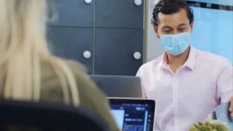 Over the Shoulder of Man In Face Mask Reading Notebook