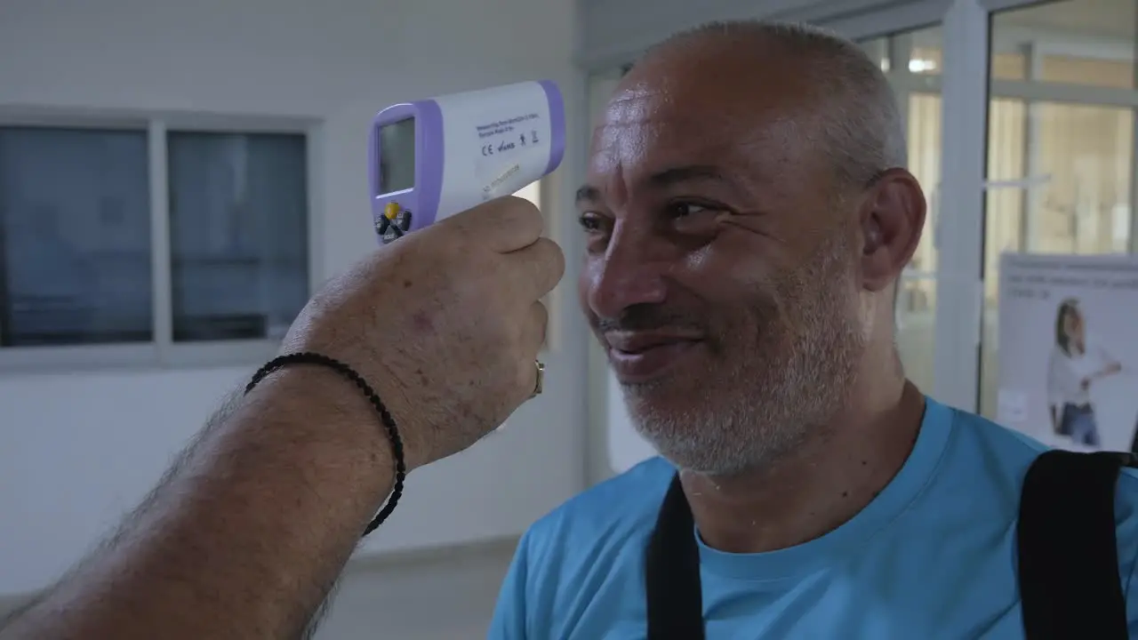 A man has his temperature checked with a touchless infrared temperature laser gun at a travel checkpoint during the COVID-19 pandemic