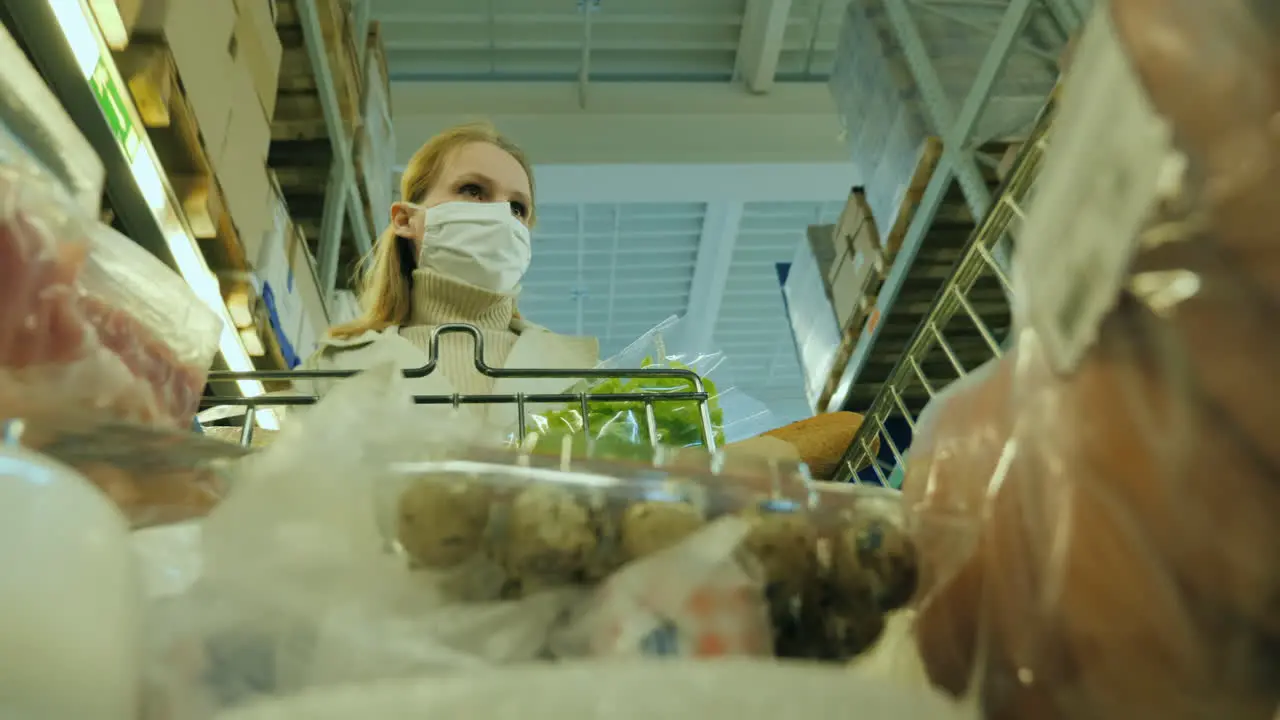 A Woman Carries A Full Shopping Trolley At The Grocery Store Wears A Protective Mask