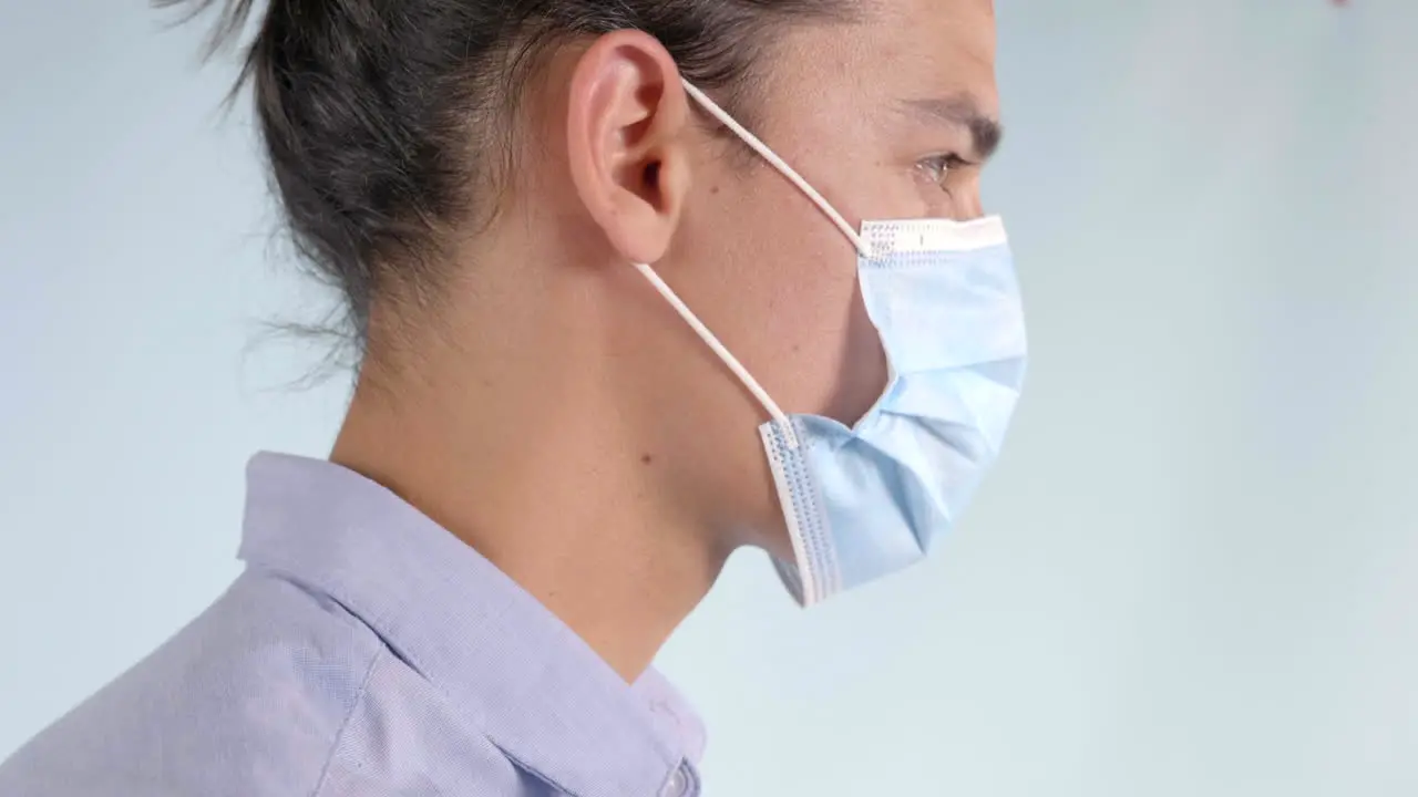 Young Man with Long Hair Putting Medical Mask on Profile shot