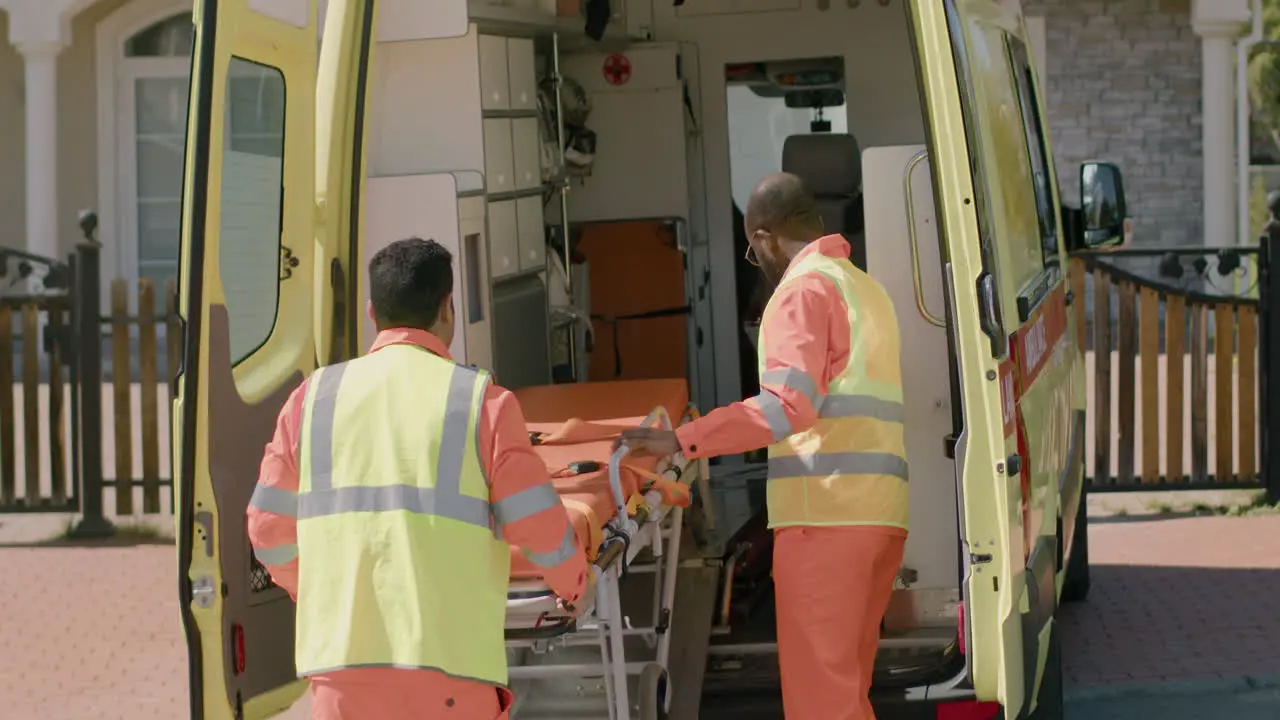 Two Paramedics Taking Medical Equipment And A Stretcher From The Ambulance To Attend A Emergency