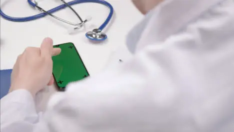 Over the Shoulder Shot of a Medical Professional Using Smartphone Touchscreen with Green Screen