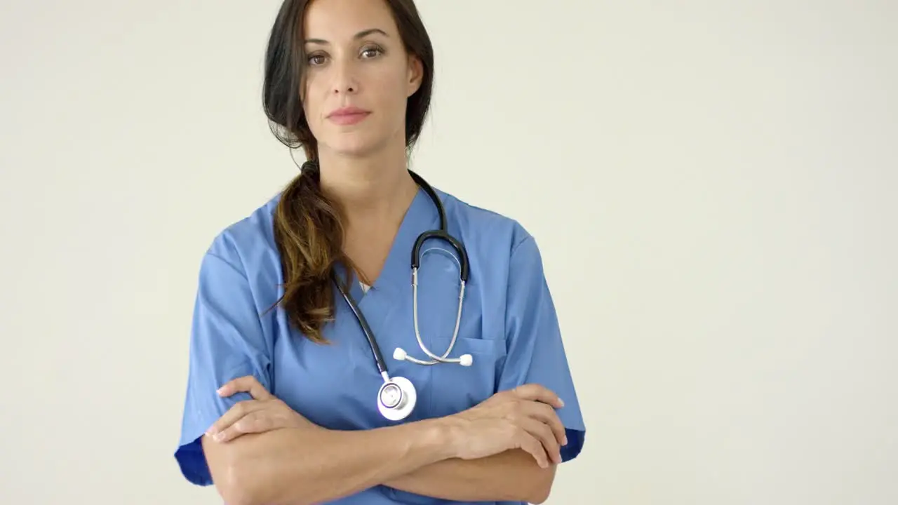 Woman in scrubs crosses arms and smiles at camera