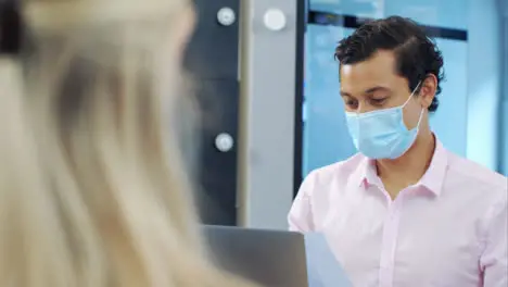 Over the Shoulder of Man In Face Mask Looking at Documents