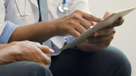 Doctor Using Tablet Whilst Talking to Patient