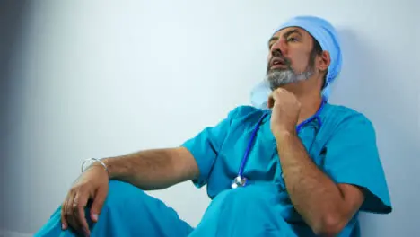 Tired Middle Aged Surgeon Removing Face Mask and Sighing with Copy Space